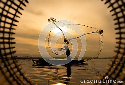 Silhouette of fisherman at sunrise, Standing aboard a rowing boat and casting a net to catch fish Stock Photo