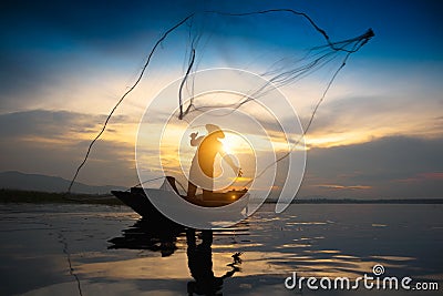 Silhouette fisherman throwing fishing net during Stock Photo