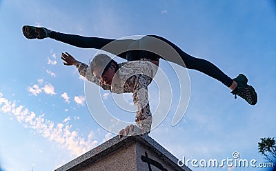 Silhouette of flexible woman doing handstand on the dramatic sunset and cityscape.Concept of desire, will and potential Stock Photo