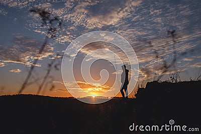 Silhouette of free woman enjoying freedom feeling happy at sunset. Serene relaxing woman in pure happiness Stock Photo