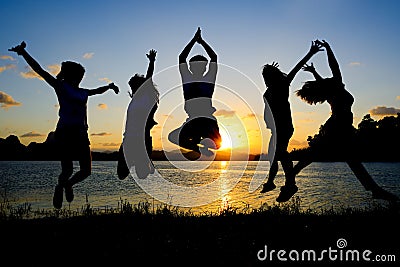 Silhouette of friends jumping in sunset Stock Photo