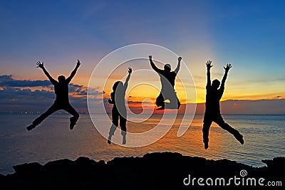 Silhouette of friends and teamwork jumping on beach during sunset time for success business. Stock Photo
