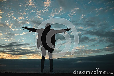 Silhouette of a man with outstretched arms to the sky Stock Photo