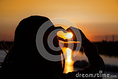 silhouette of hands forming a heart shape with sunset. expression of love and gratitude to the world. Stock Photo