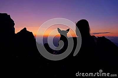 SILHOUETTE: Girl and her dog watch the sunset after a hiking trip in Julian Alps Stock Photo