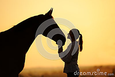 Silhouette of girl with horse at the sunset Stock Photo