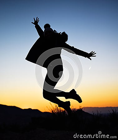 Silhouette of girl jumping in the middle of nature on winter against sunset Stock Photo