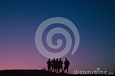 Silhouette of a group of five friends standing in front a pink sunset Stock Photo