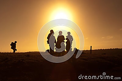 Soldiers standing against sunset Stock Photo