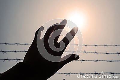 Silhouette hand extending to the sky with barbwire and sunlight, vintage tone Stock Photo