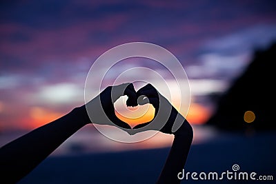 Silhouette hand in heart shape with sunset in the Stock Photo