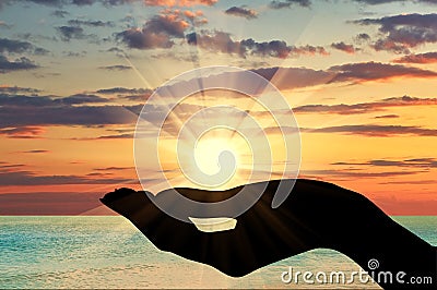 Silhouette of a hand holding the sun Stock Photo