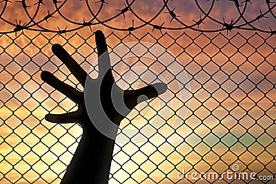 Silhouette hands refugee near the fence of barbed wire Stock Photo