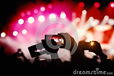 Silhouette of hands using smartphones to take pictures and videos at live music show Stock Photo