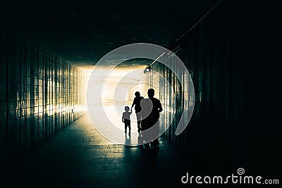 Silhouette of happy family with children. Mother and daughter holding hands. Father and baby in stroller going behind. Stock Photo