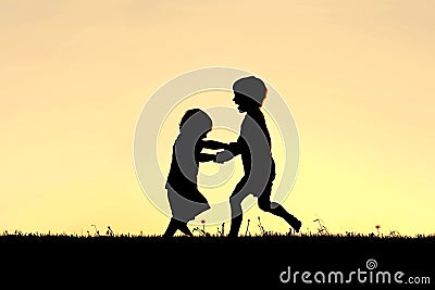 Silhouette of Happy Little Children Dancing at Sunset Stock Photo