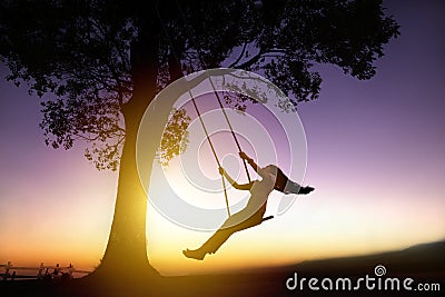 Silhouette of happy young woman on swing Stock Photo