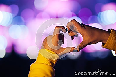 Silhouette of a heart shaped hands and crowd of Audience at live concert, light illuminated is power of music concert Stock Photo