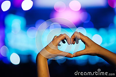 Silhouette of a heart shaped hands and crowd of Audience at live concert, light illuminated is power of music concert Stock Photo