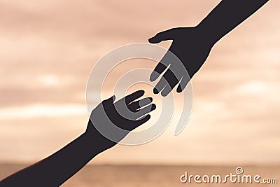 Silhouette helping hands on blurred sea and sky background Stock Photo