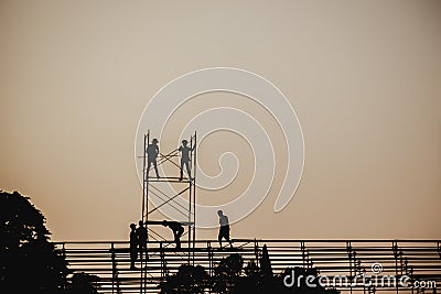 Silhouette image of a group of workers working on scaffolding for construction Stock Photo