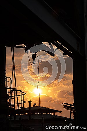 Silhouette industrial hook crane in sunset background Stock Photo