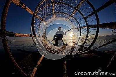 Silhouette of intha fisherman against the sunset sky Stock Photo