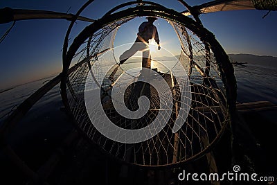 Silhouette of intha fisherman against the sunset sky Stock Photo