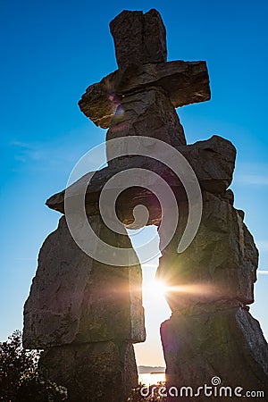 Figure of inukshuk on the seacoast against the sunset. Inukshuk at English Bay Beach in Vancouver BC Stock Photo