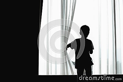 Silhouette of kid opening curtain Stock Photo