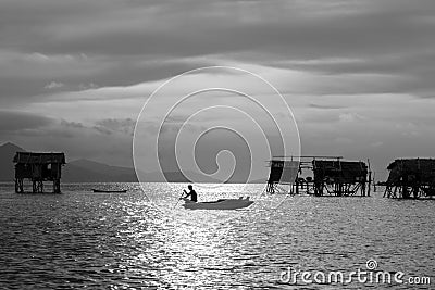 Silhouette of a kid paddling on a boat near Bajau Laut village in Maiga Island in Semporna, Sabah Borneo, Malaysia. Image in Black Editorial Stock Photo