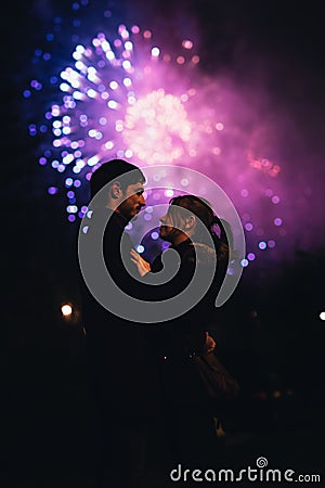 A silhouette of a kissing couple in front of a huge fireworks display. Stock Photo