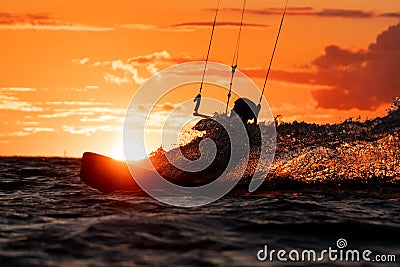 Silhouette of kitesurfer riding in orange sunset with the sun right behind Stock Photo