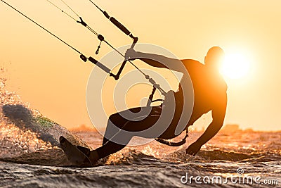 Silhouette of kitesurfer riding in sunset conditions with sun behind and lens flare Stock Photo