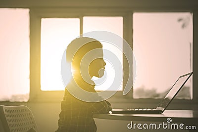 Silhouette of little boy watches a movie on a laptop Stock Photo