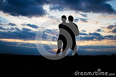 Silhouette lovely couple in a field at sunset with a dramatic sky Stock Photo