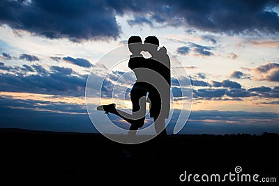 Silhouette lovely couple in a field at sunset with a dramatic sky Stock Photo