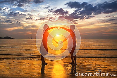 Silhouette of loving couple during an amazing sunset, holding hands in heart shape. Love. Stock Photo
