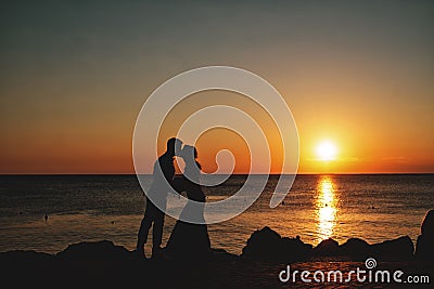 Silhouette of a loving, married couple where he is kissing her h Stock Photo