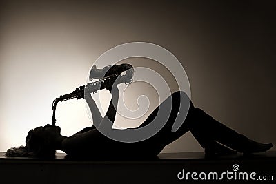 Silhouette of lying woman playing saxophone Stock Photo