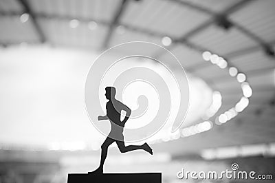 Silhouette of a Male Athlete, a Dedicated Runner, Showcasing Tenacity Amidst the Serene Evening Glow of a Modern Sports Stadium Stock Photo