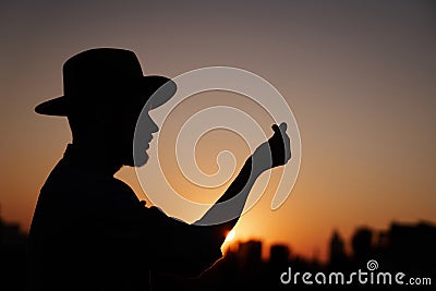 Silhouette male in hat showing korean heart at sunset Stock Photo