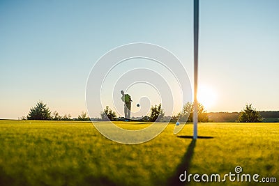 Silhouette of a male player hitting a long shot on the putting g Stock Photo