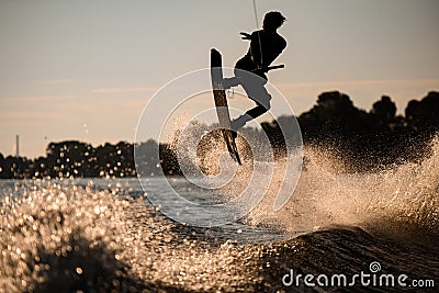 silhouette of male wakeboarder who having fun and jump on the board over splashing river wave Stock Photo