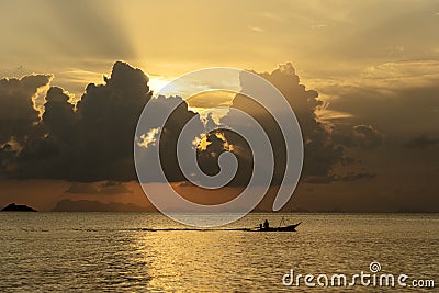 Silhouette of a man on a boat during sunset at sea Stock Photo