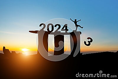 Silhouette of man change 2023 to 2024 on the top of the building at sunset sky. Concept for preparation of welcome 2024 new year Stock Photo