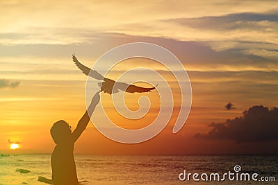 Silhouette of man feeding seagull at sunset Stock Photo