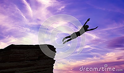 Silhouette of a Man Jumping off a Cliff Stock Photo