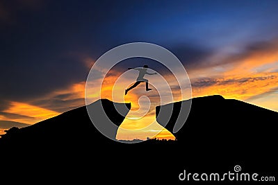 Silhouette of man jumping over cliff on sunset background Stock Photo