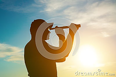 A silhouette of a man looking at using a monocular telescope against a dramatic sky at sunset. business idea concept, look to the Stock Photo